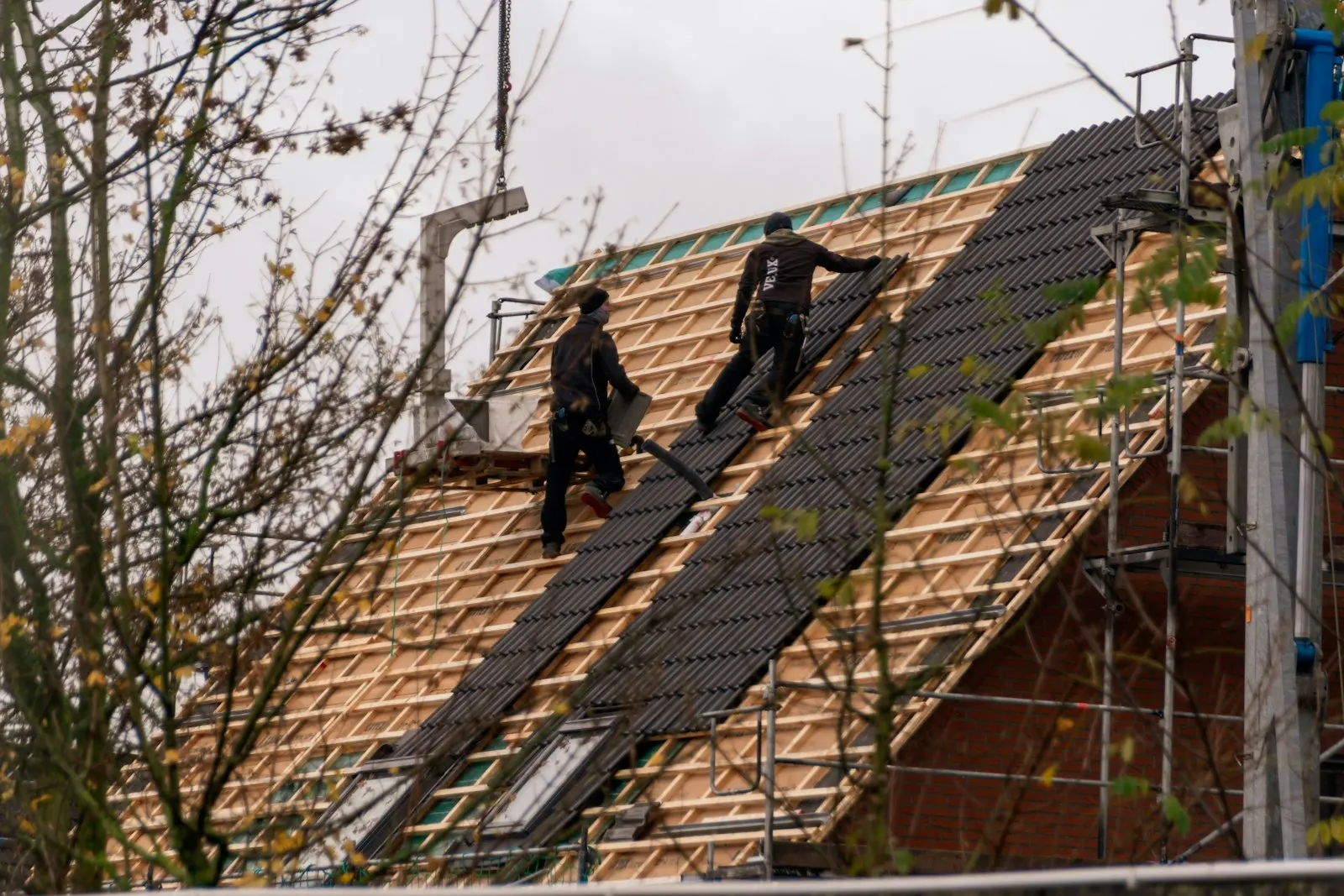 Roofers installing shingles on a steep residential roof