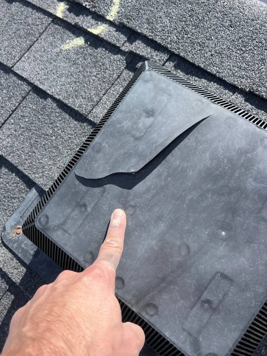 A cracked plastic roof vent, split by hail impact